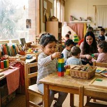 A toddler stacking coloured rings at a classroom table