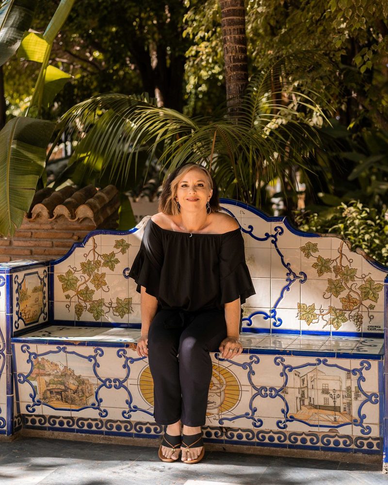 Leah Retamozo, MEd, founder and CEO of Bilingual Child Care & Education Center, seated on a Spanish tiled bench
