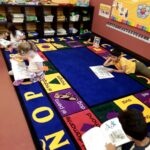 A group of children sitting on the floor in front of books.