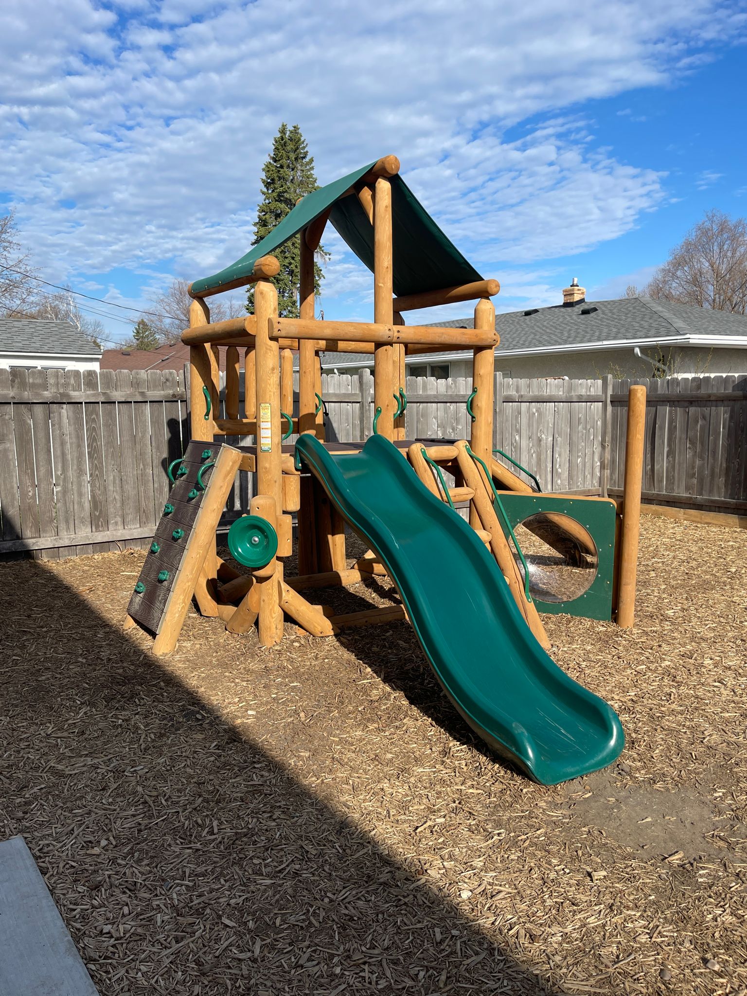 A wooden play structure with a slide and swing set.