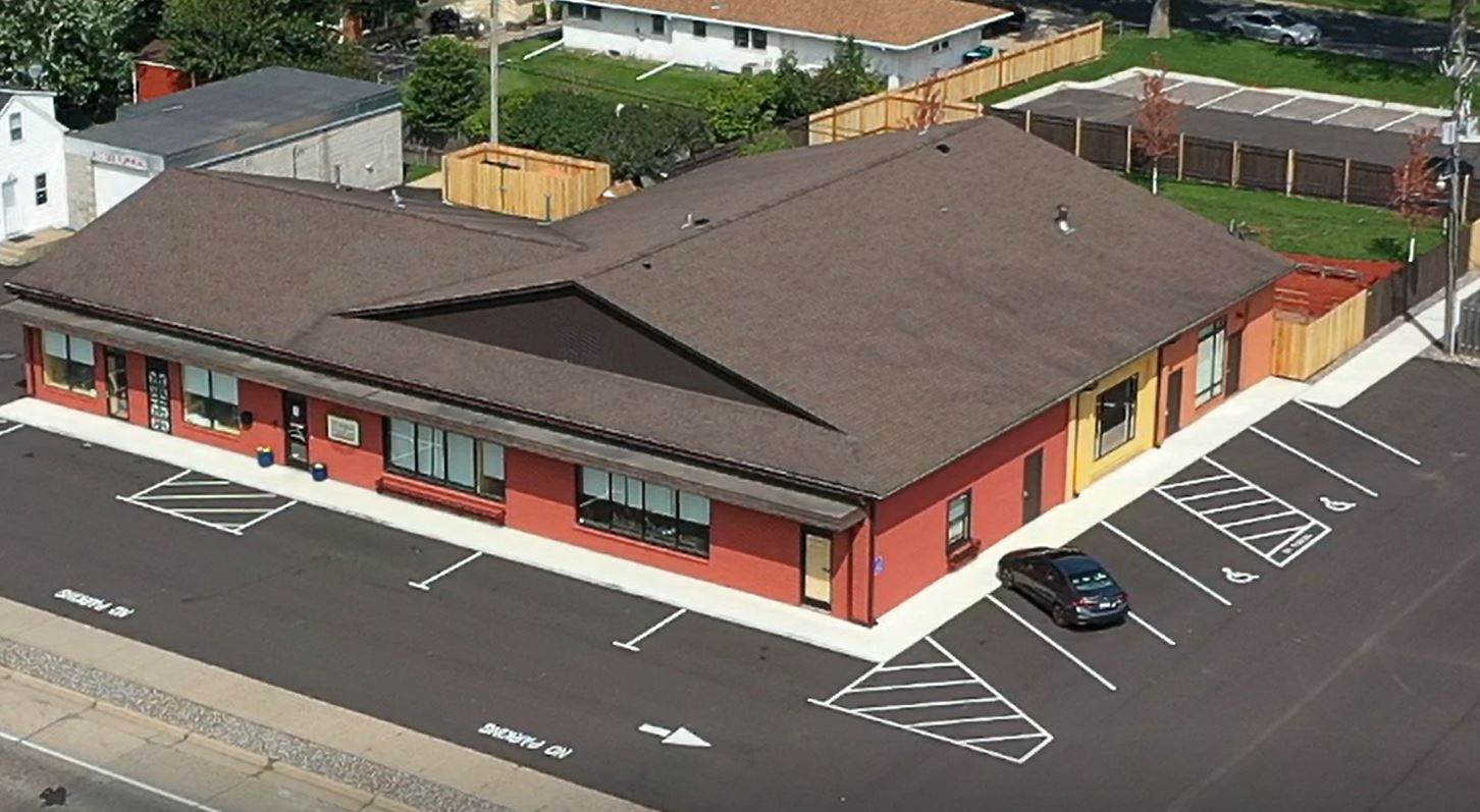 A red building with brown roof and cars parked in front of it.