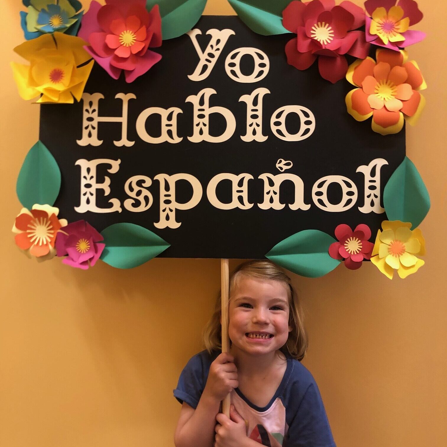 A girl holding onto a sign that says " yo hablo espanol ".