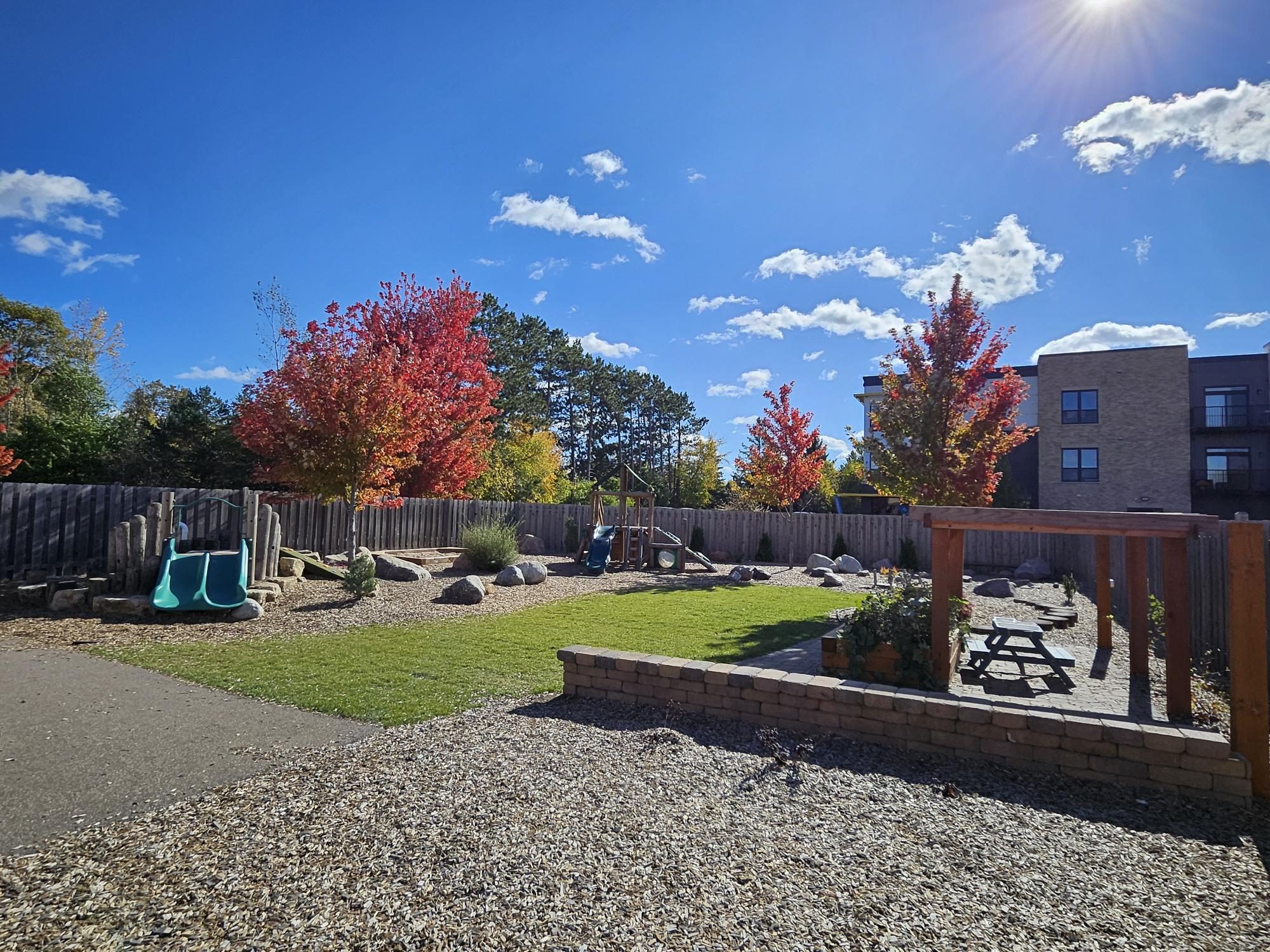 The Mahtomedi playground in autumn color, with a teal slide structure and picnic pergola