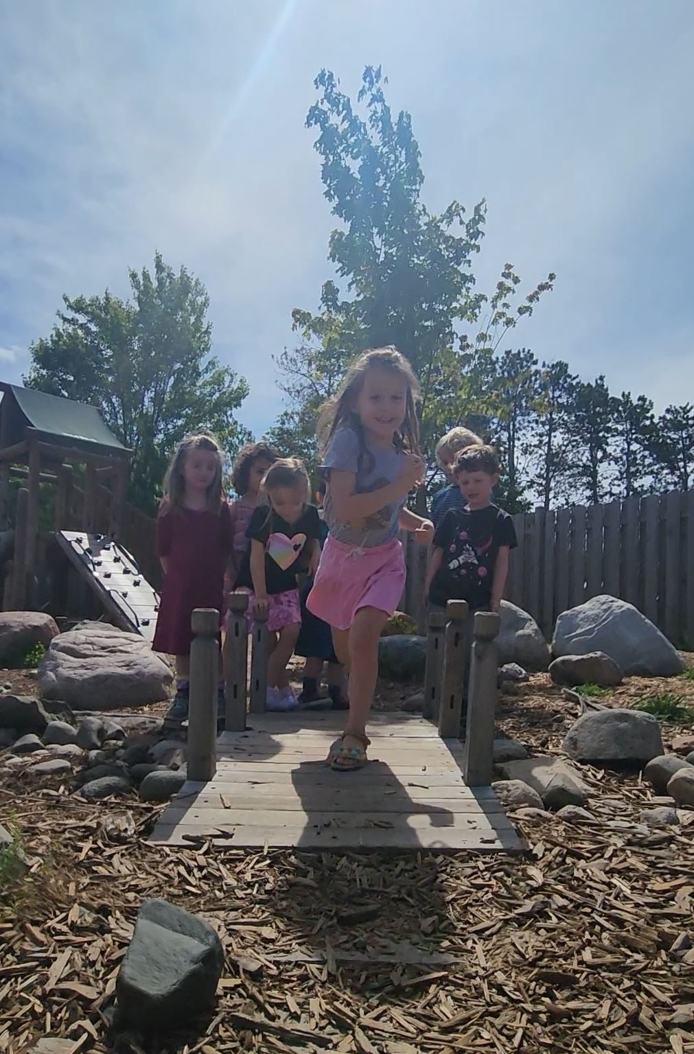 Children crossing the wooden bridge on the natural playground