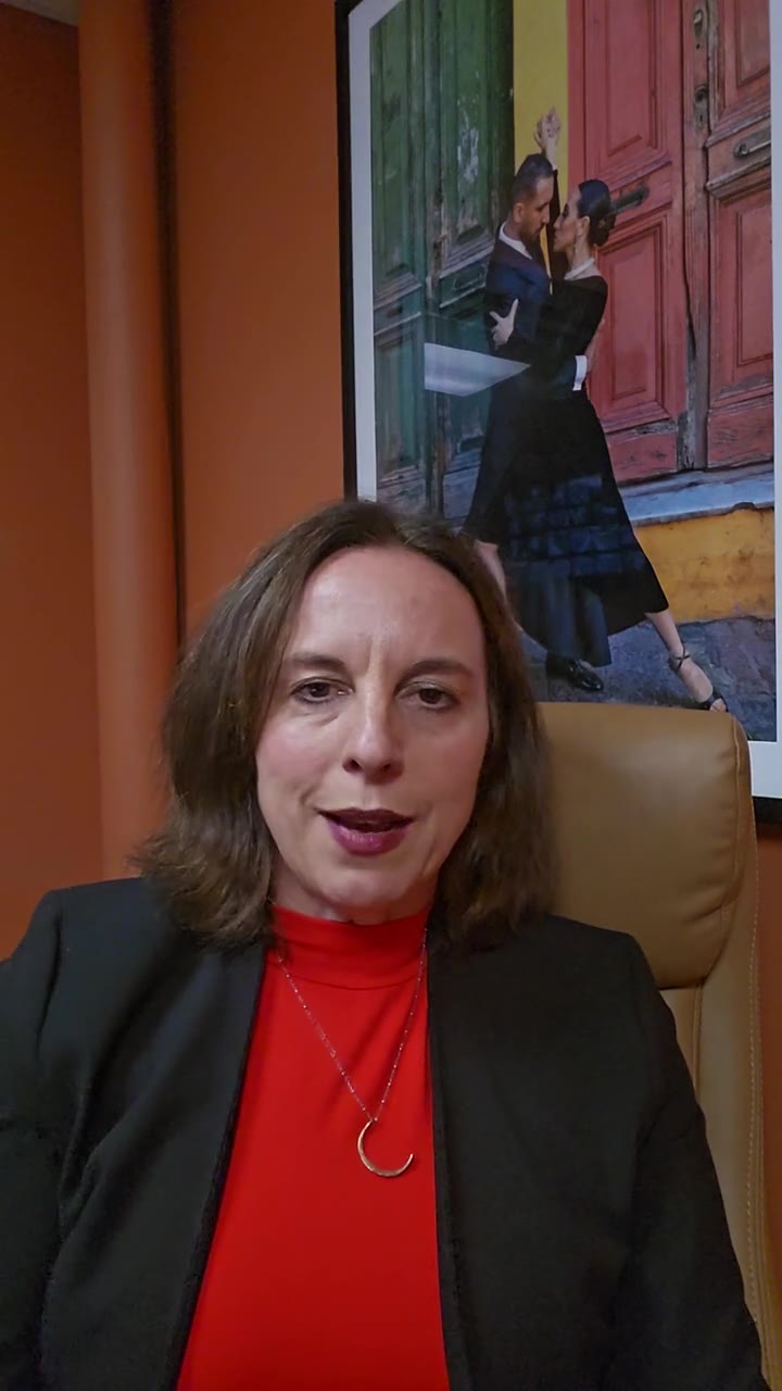 Leah Retamozo seated in her office in front of an orange wall, talking to camera about the curriculum