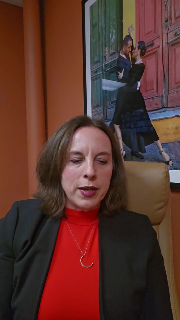 Leah Retamozo seated in her office in front of an orange wall, talking to camera about the foundations